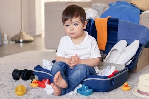 Child sitting in unpacked luggage