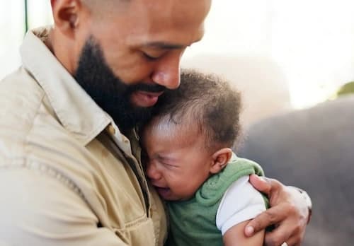 Baby crying in fathers arms