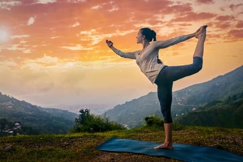 Woman holding dancer position on a yoga mat