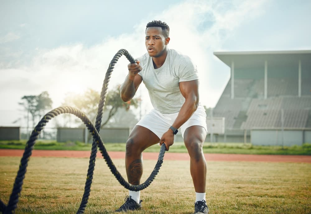 Man working out with heavyweight ropes in an open field