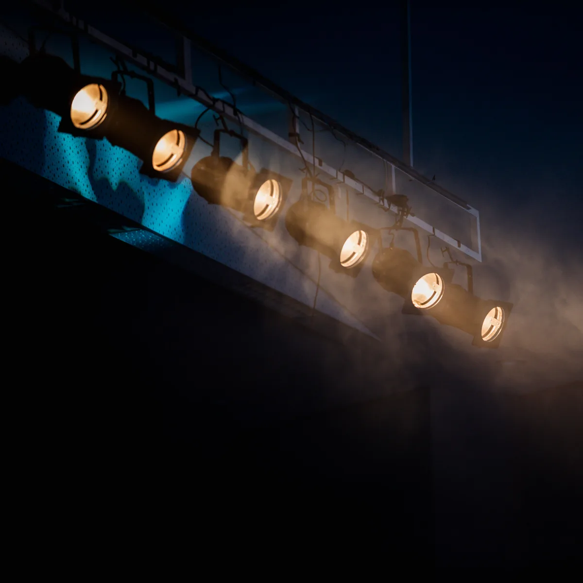 Stage spotlights cutting through haze above a fashion show runway